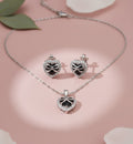 Silver heart-shaped jewelry set with necklace and earrings on a pink background