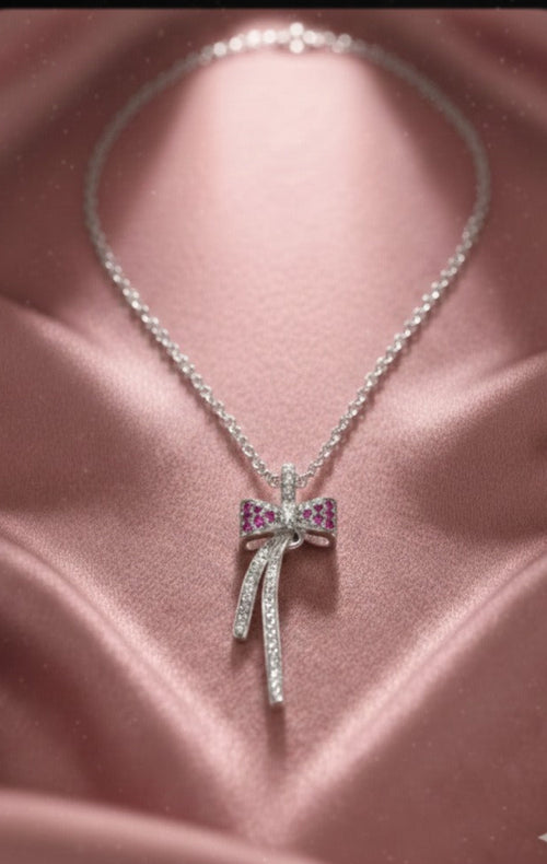 Silver necklace with a bow-shaped pendant on a pink satin background