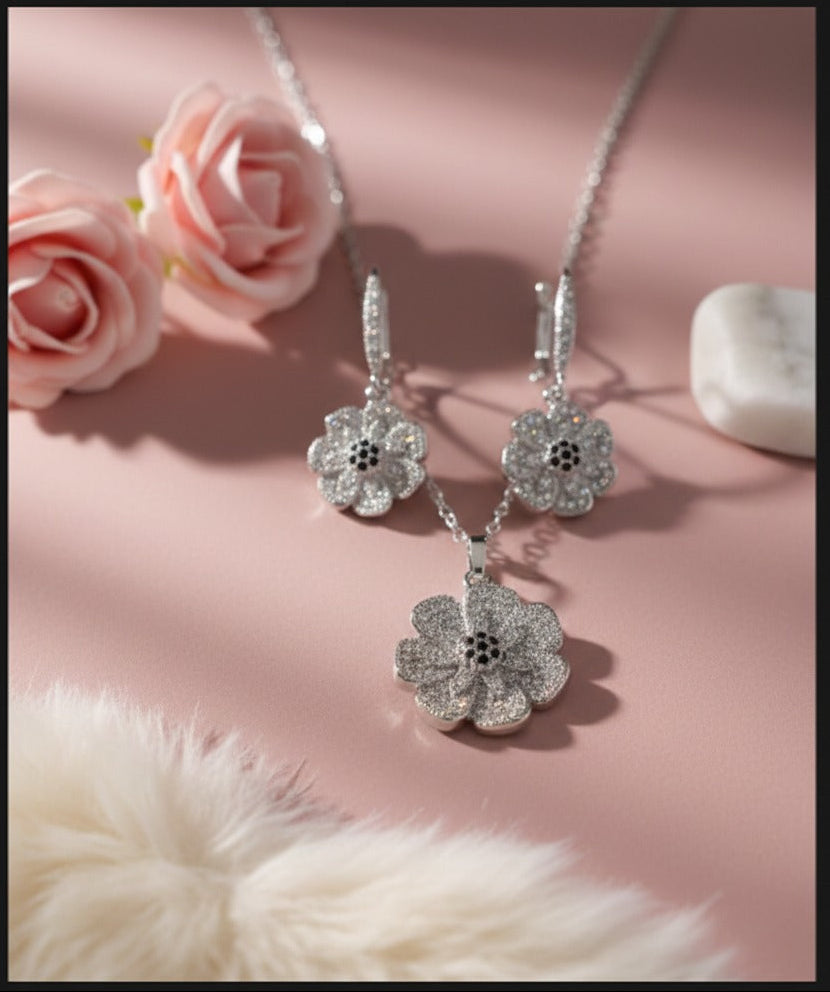 Silver floral jewelry set with earrings and necklace on a pink background with flowers and fur.