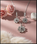 Silver floral jewelry set with earrings and necklace on a pink background with flowers and fur.