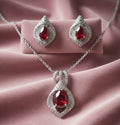 Jewelry set with red gemstones and silver accents on a pink fabric background