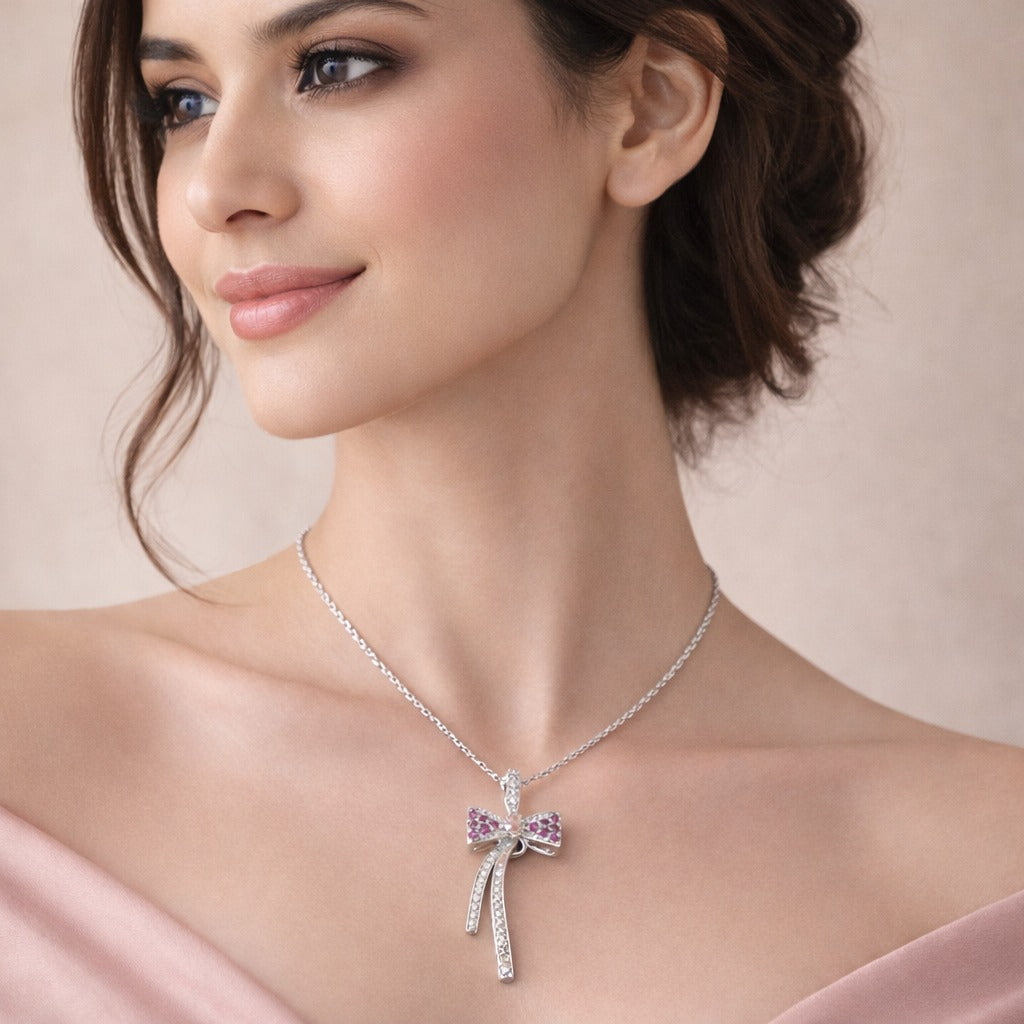 Woman wearing a silver necklace with a pink bow pendant against a beige background