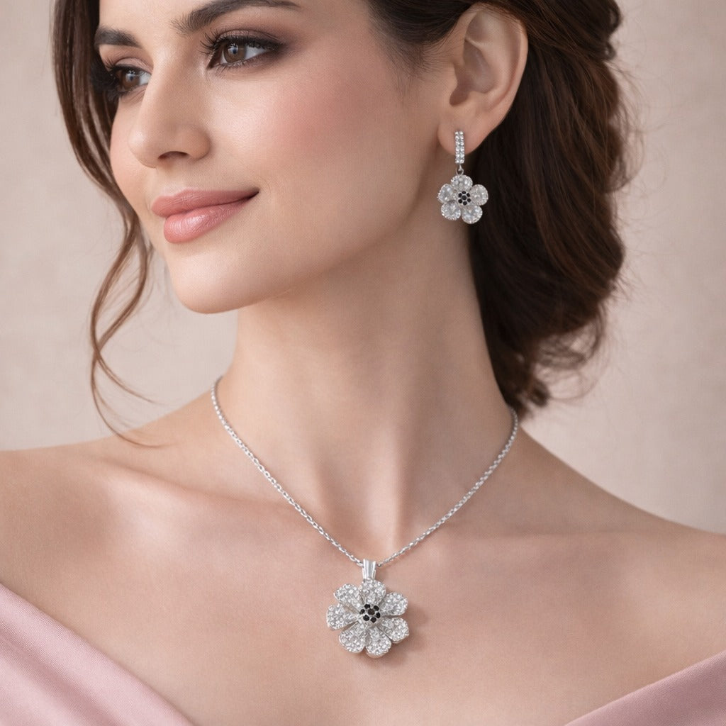 Woman wearing a silver flower necklace and earrings against a neutral background