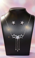 Star-shaped necklace and earrings on a black mannequin with a soft pink background